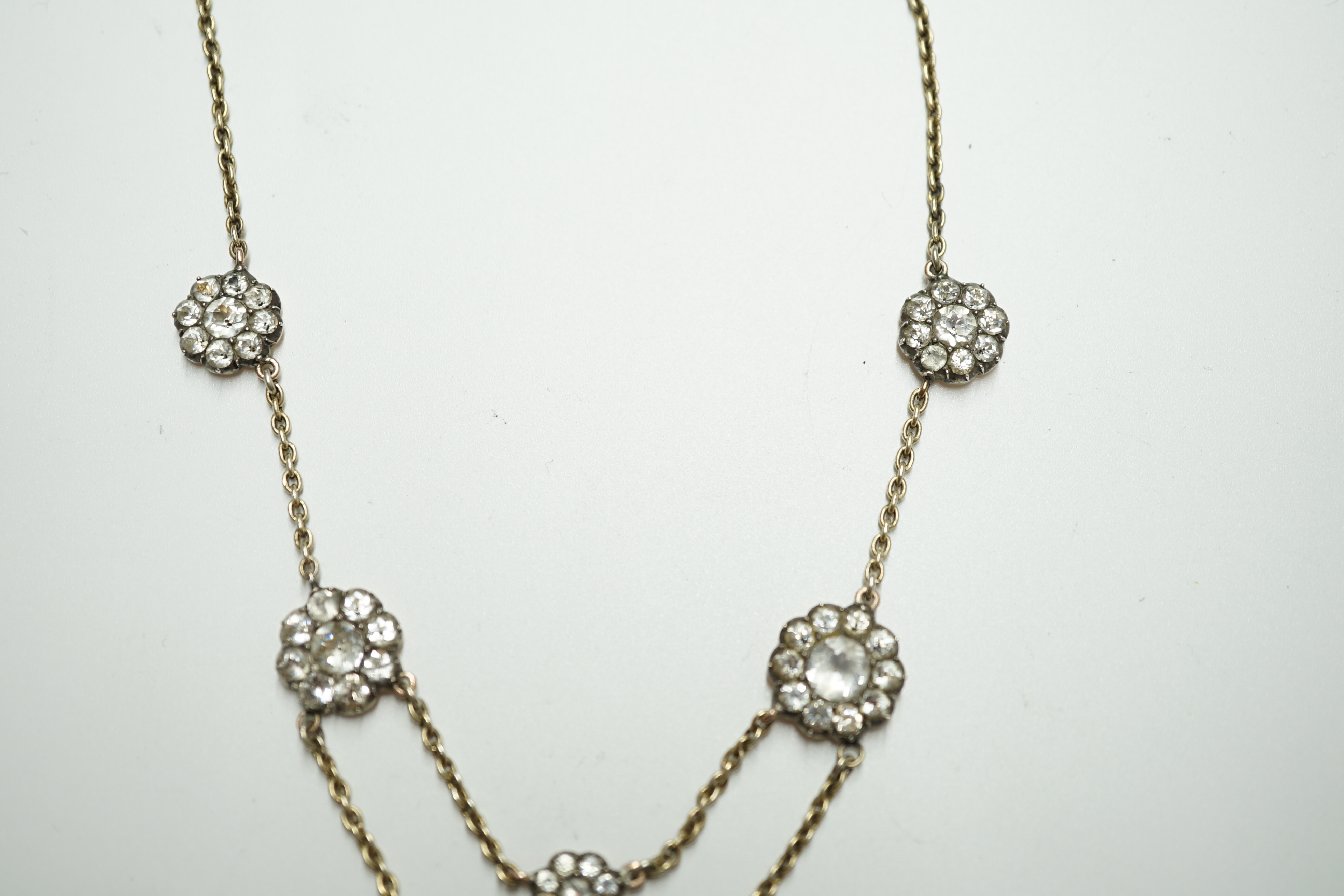 An early 20th century yellow metal and paste set multi flower head necklace, 39cm, gross weight 10.7 grams. Condition - poor to fair